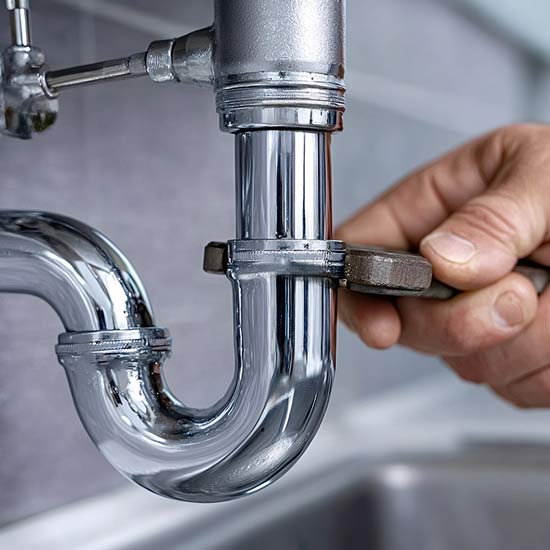 Person using a wrench to tighten a plumbing pipe