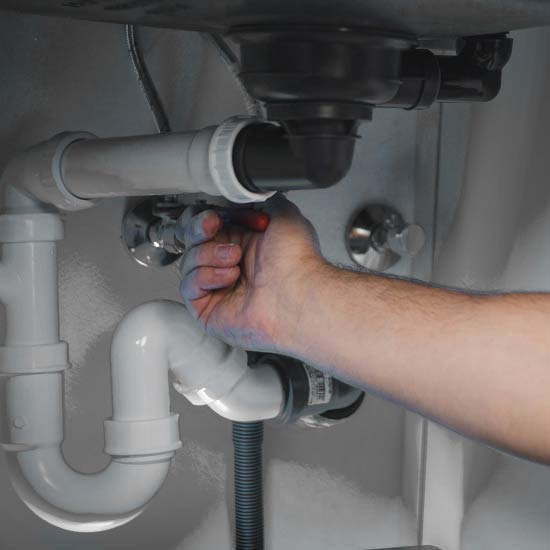 Plumber working under a sink