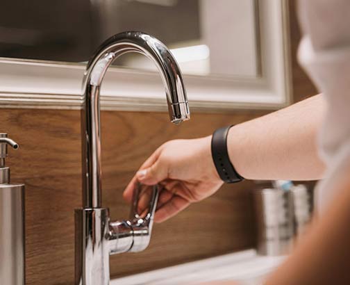 Someone turning on the faucet on a repaired bathroom sink