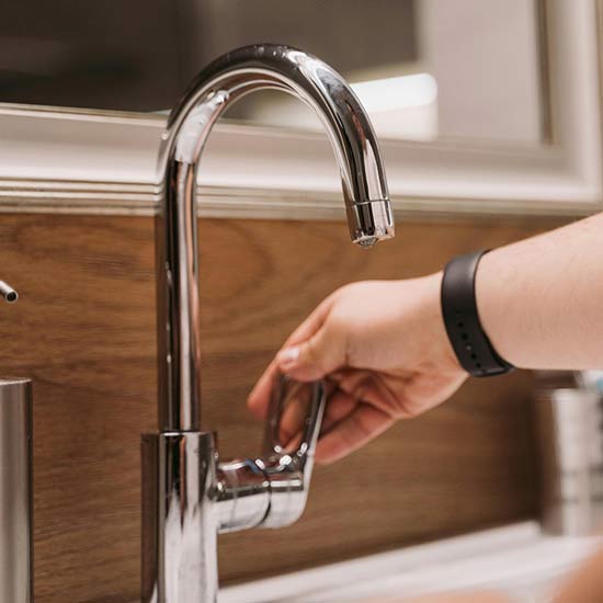 Someone turning on a clean, modern sink