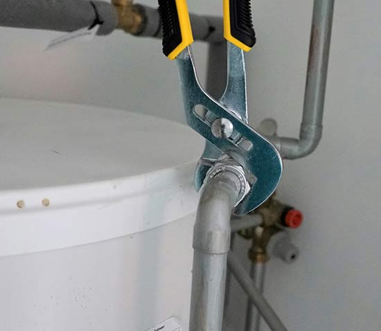Wrench being used on water heater pipes